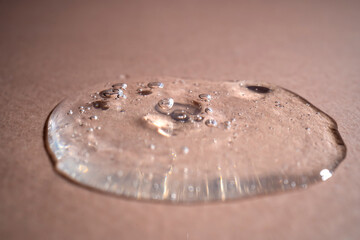 A drop of serum with bubbles on a beige background.