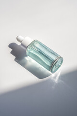A blue transparent bottle with serum in the rays of the sun.
