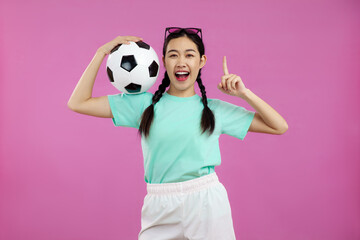 Happy Asian woman over isolated pink background holding a soccer ball, sport concept