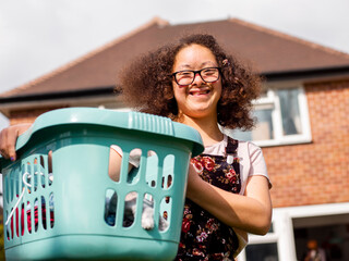 Portrait of girl holding laundry basket in backyard