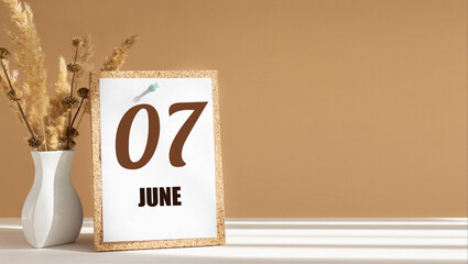 june 7. 7th day of month, calendar date.White vase with dead wood next to cork board with numbers. White-beige background with striped shadow. Concept of day of year, time planner, summer month