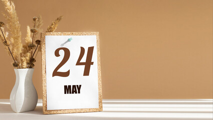 may 24. 24th day of month, calendar date.White vase with dead wood next to cork board with numbers. White-beige background with striped shadow. Concept of day of year, time planner, spring month