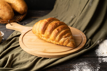 fresh croissant on wooden board, green fabric background, homemade baking