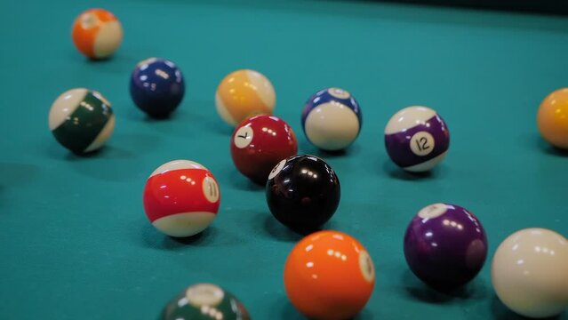 Close up: breaking racked colorful pool balls on teal billiard table - slow motion. Sport, game, competition, hobby and leisure time concept