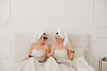 Obraz na płótnie Canvas Two stylish women in jewelry resting in bedroom
