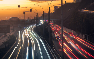 Fototapeta na wymiar Moving lighs of cars along the road in sunset