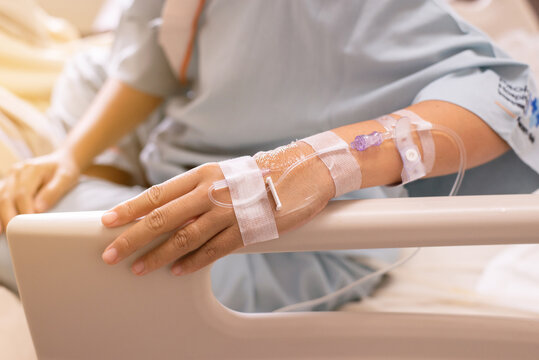 Hands patient woman receiving saline solution during sitting on sick bed at hospital