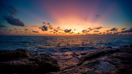 Blurred nature background of the morning sun by the sea, a beautiful golden light, among the trees, rocks and local fishing boats, the beauty of nature during the day.