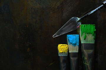 Three artists paint brushes with primary yellow, teal and phthalo green on bristles with paint...