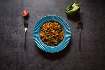 Vegetable spiral pasta served in a blue bowl on a dark background. Top view.