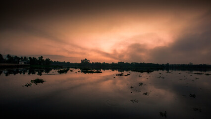 Blurred nature background of the morning sun by the sea, a beautiful golden light, among the trees, rocks and local fishing boats, the beauty of nature during the day.