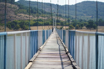 Male silhouette in the middle of an endless rope bridge