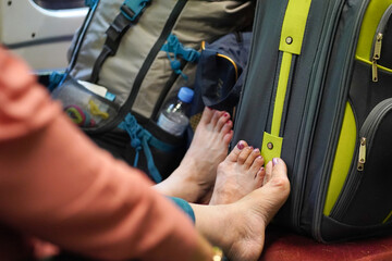 Women traveling on a train with their shoes on with luggage and feet with lacquered toenails on the seat