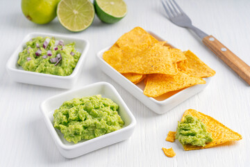 Two variants of homemade mexican guacamole dip, sauce or spread made of mashed avocado with cut red...