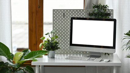 Comfortable workplace with computer pc, supplies and decorating with green potted plants.