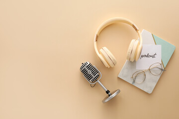 Microphone, headphones, paper with word PODCAST and notebook on color background
