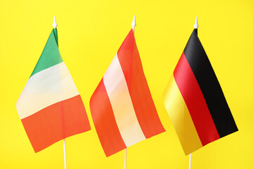 Flags of Italy, Austria and Germany on yellow background, closeup