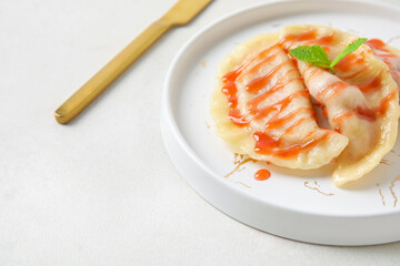 Plate with tasty strawberry dumplings and jam on light background, closeup