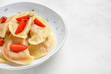 Bowl with tasty strawberry dumplings on light background, closeup