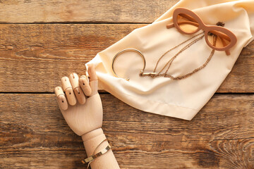 Decorative hand with stylish accessories on wooden background