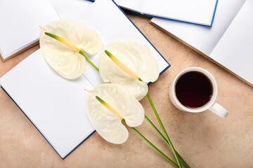 Beautiful anthurium flowers with books and cup of coffee on color background