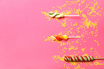 Sweet lollipops and colorful sprinkles on color background