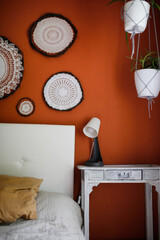 Console table with a lamp by the bed, decor on the wall of crocheting napkins and wreaths, home decoration