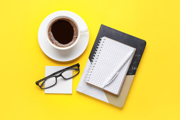 Fototapeta na wymiar Composition with cup of coffee, notebooks and eyeglasses on color background