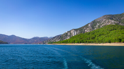 Obraz premium View of the green water of the Oymapinar Dam with green trees on the shore