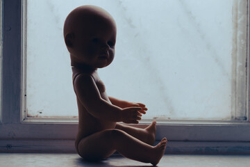 baby doll sits near the window. child accident concept
