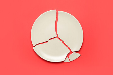 Broken ceramic plate on red background