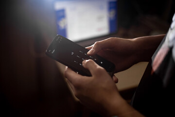 A man dials a number that starts with plus 4 on his smartphone. Dark background.