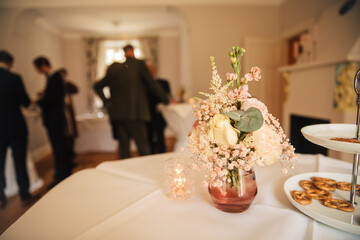 Flowers as a decoration on a table. champagne reception inside. receive guests