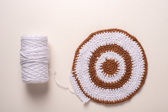 Redonda de crochet (ganchillo) de hilo, c&iacute;rculo en baretas o punto alto de dos colores, blanco y marr&oacute;n. Con ovillo