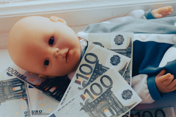 baby doll lies with euro money. children sale concept