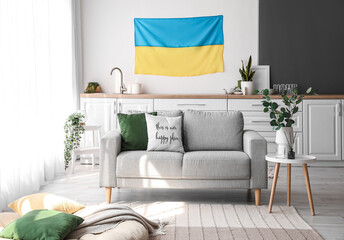 Interior of light kitchen with hanging Ukrainian flag, counters and sofa