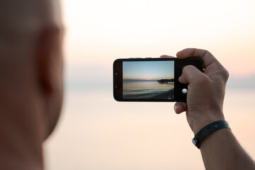 Man taking photo amazing sunset using smartphone camera, tourist hand holding cell phone, taking photo of nature landscape in travel, photography outdoors, blur background