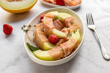 Honeydew melon with strawberry and prosciutto ham.