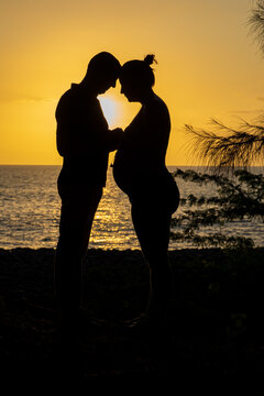 Silhouette de couple, homme et femme enceinte devant la plage au coucher du soleil