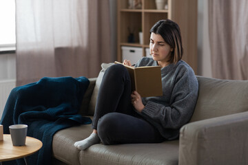 people, leisure and depression concept - sad woman with diary sitting on sofa at home