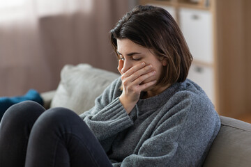 Fototapeta premium mental health, psychological problem and depression concept - stressed woman sitting on sofa at home