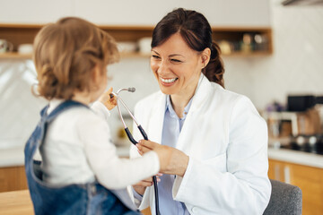 Smiling brunette pediatrician, taking care of her little patient