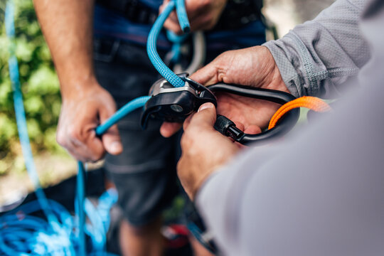 Close up of a people using a hook, tying a rope, preparing for climbing.