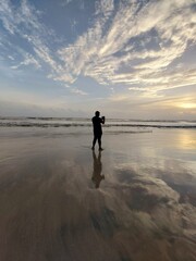 silhouette of man taking photo of the sunset at the beach