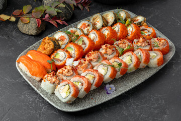 Set of tasty sushi rolls and sashimi on tray in studio