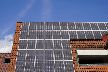 Solarmodule auf einem sehr grossen Ziegeldach. Im Dach ist ein kleiner Balkon integriert.