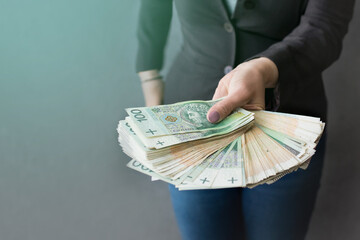 Kobieta wyciąga przed siebie ręce pełne pieniędzy, dużo pieniędzy w dłoni