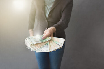 Kobieta wyciąga przed siebie ręce pełne pieniędzy, dużo pieniędzy w dłoni - obrazy, fototapety, plakaty
