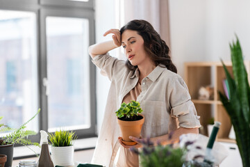 people, gardening and housework concept - tired woman planting pot flowers at home