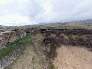 panoramic view of the Caucasus Mountains gorges ancient fortresses and curved mountain roads on a spring day taken from a drone